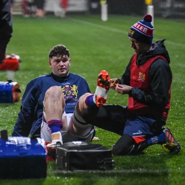 Physiotherapist treating a rugby player on the sideline