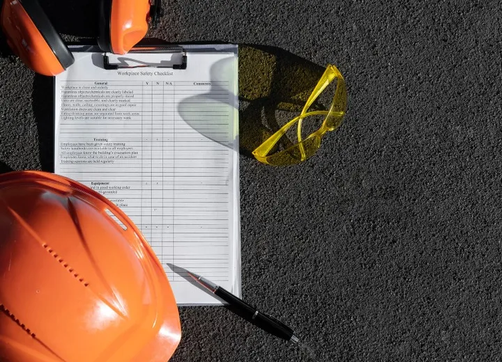 Hard hat, safety glasses and clipboard on a work site